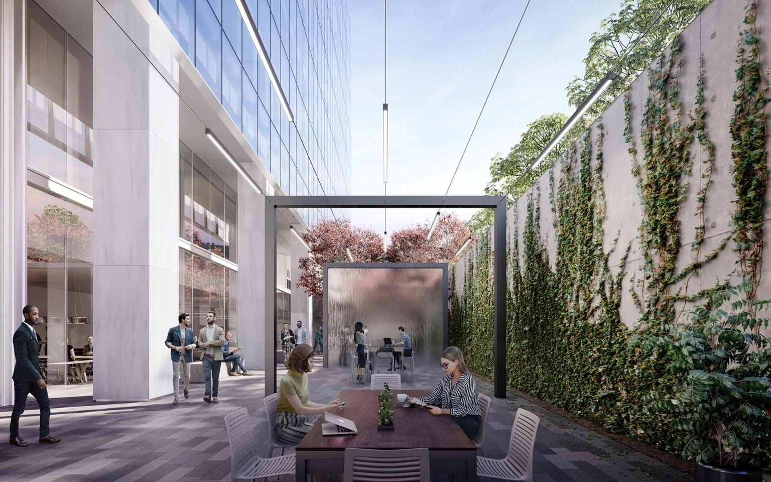 Outdoor conference area at 23Springs with work tables, ivy-covered walls, shaded structure, and people engaged in conversation and laptop work.