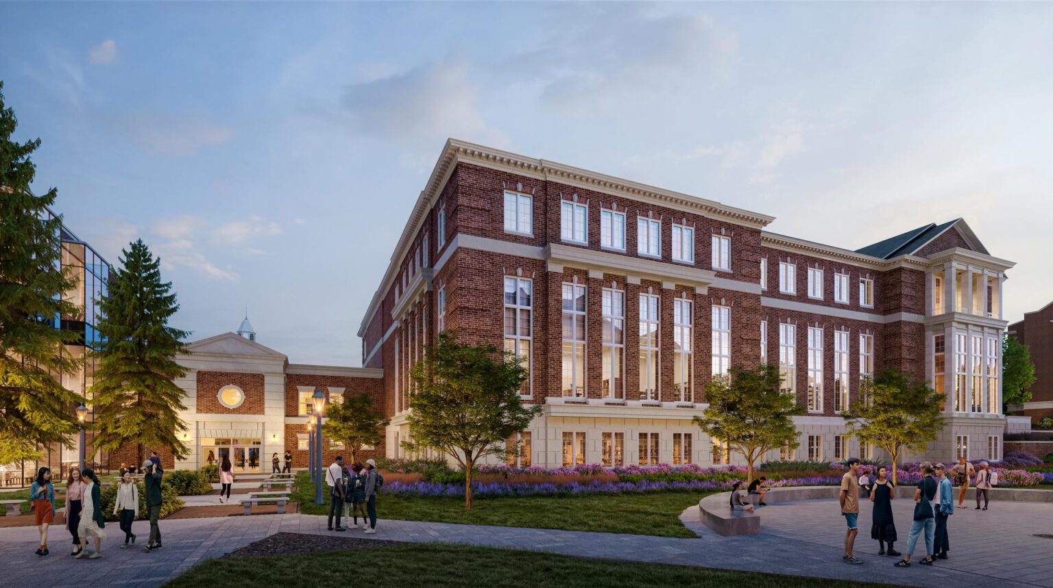 Evening view of library corner with tall windows, rich brick detailing, and students gathering in a landscaped public space.