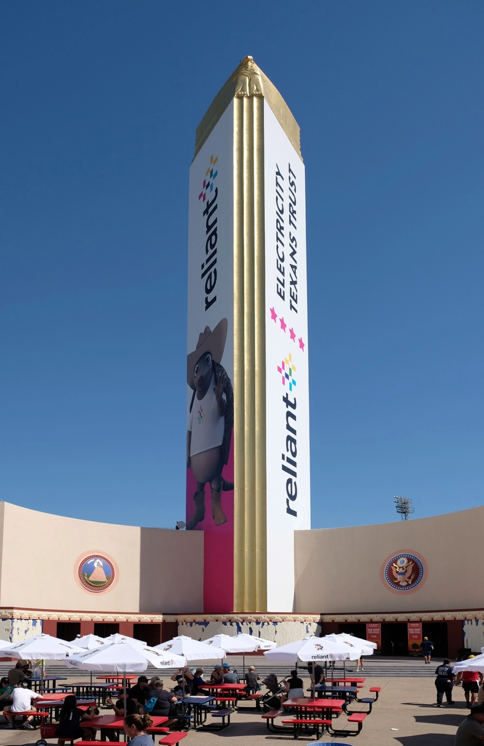 Fair Park Tower Building with its gold-clad spire and surrounding seating plaza on a sunny day.