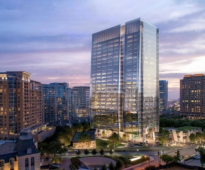 Skyline view of 23Springs in Uptown Dallas at dusk, showing the glass tower above its landscaped plaza and two street-facing restaurant buildings.