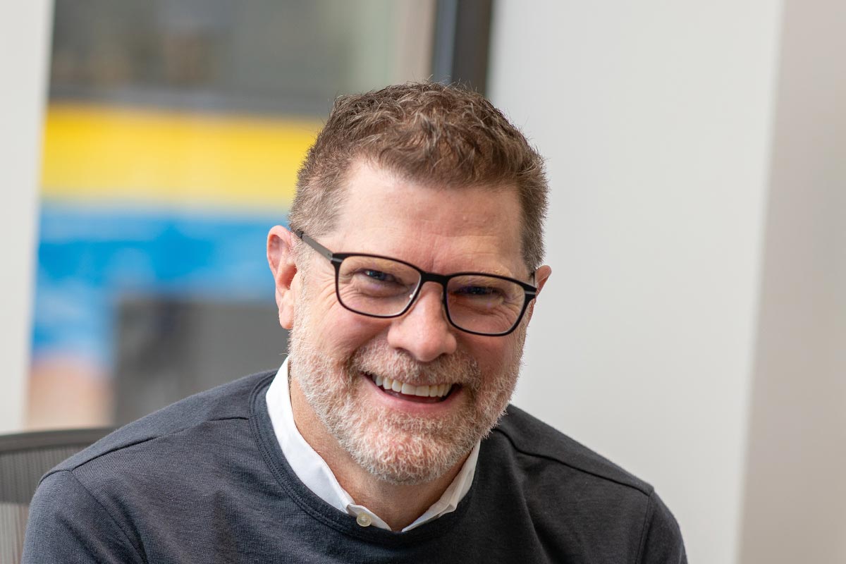 Jim West, AIA, LEED AP, NCARB, Principal and Managing Director of GFF Austin, close-up headshot in a dark sweater with blurred office background.