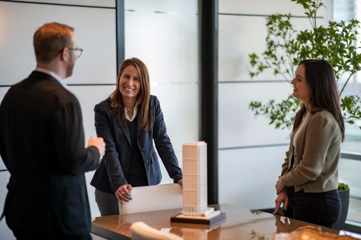 Maria Gomez, AIA, LEED AP, Principal and Studio Director at GFF, leading a discussion around a conference table with colleagues and a building model, emphasizing collaborative design leadership.