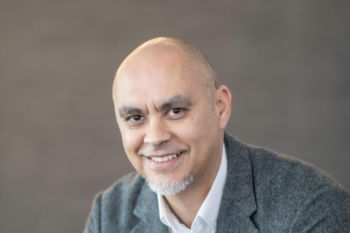 Ricardo Montoya, Principal at GFF, close-up portrait with warm studio lighting and gray background.