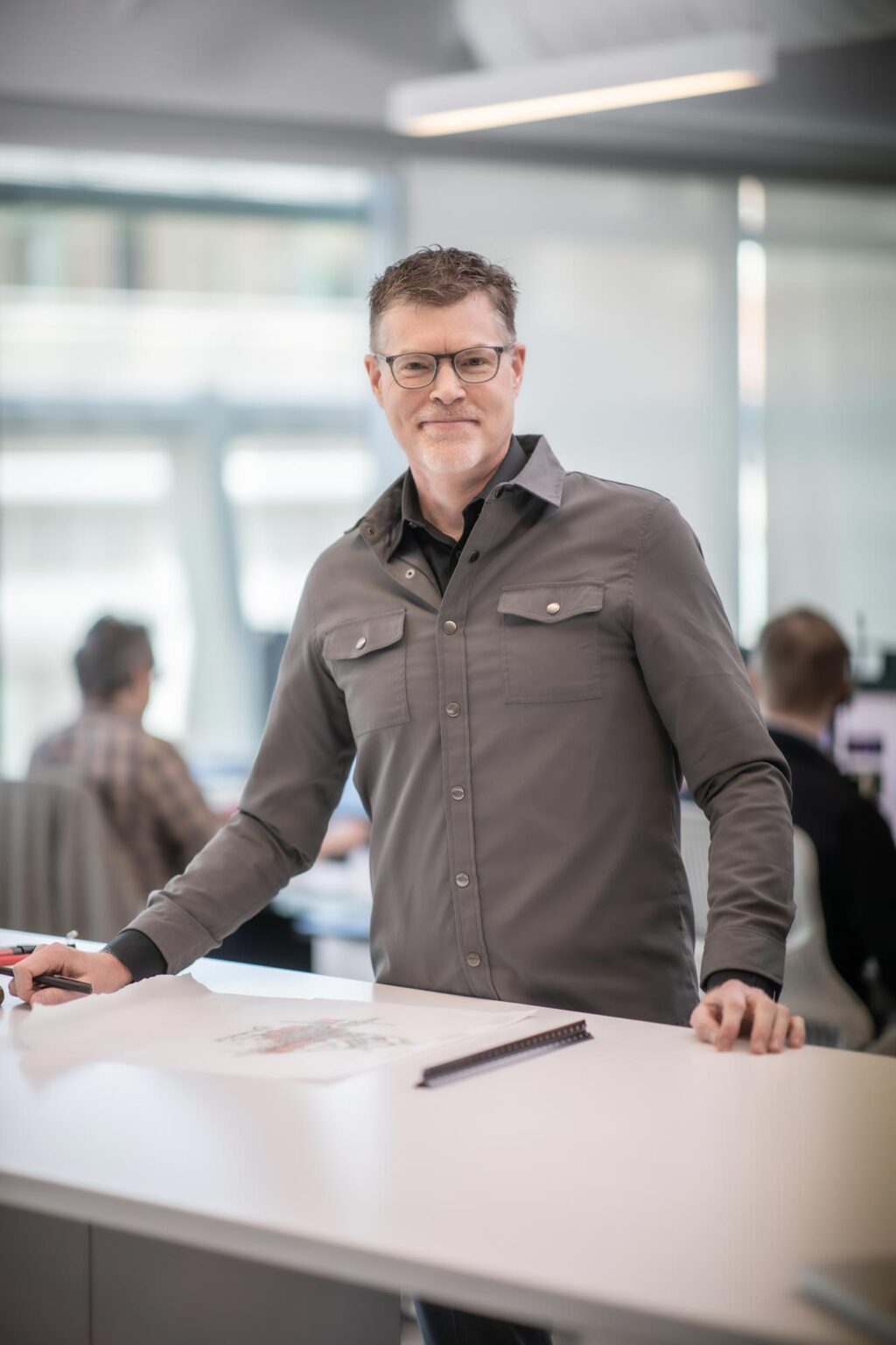 Brian Moore, Principal and Director of Planning at GFF, standing at a worktable reviewing site plans in a bright studio environment.