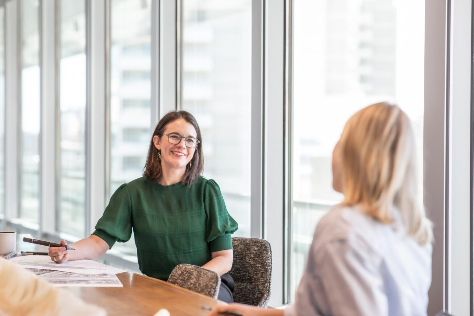 Jacquelyn Block, AIA, LEED AP, Principal and Director of Faith & Community Practice at GFF, leading a collaborative design discussion at a table with natural light from tall windows.
