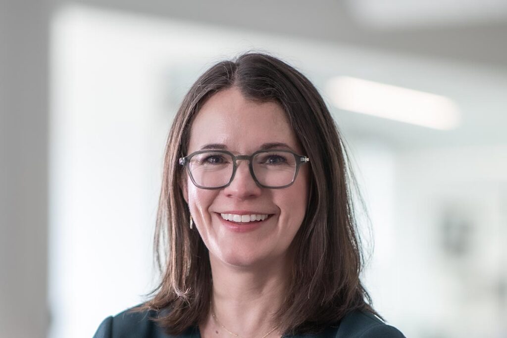 Jacquelyn Block, AIA, LEED AP, Principal and Director of Faith & Community Practice at GFF, close-up portrait with glasses in soft-focus office background.