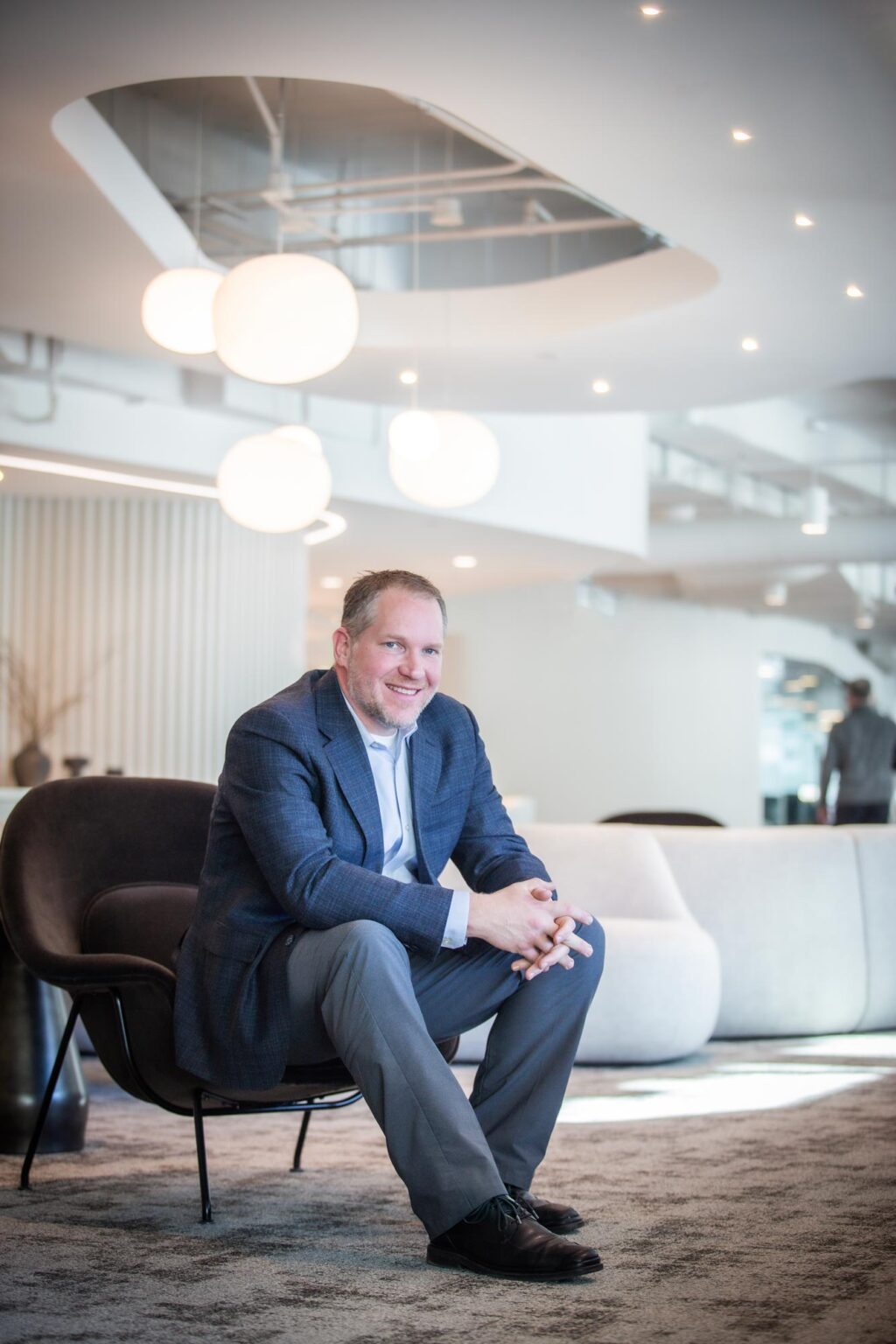 Andrew Adkison, architect and design leader at GFF, seated in a modern Dallas workplace lounge with contemporary interior design elements.