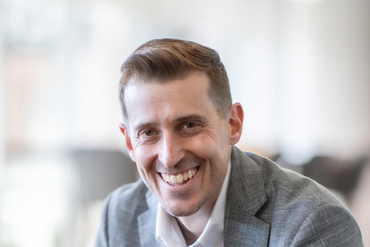 Jason Cave, Associate Principal and Director of Civic Practice at GFF, close-up portrait in soft daylight wearing gray blazer.