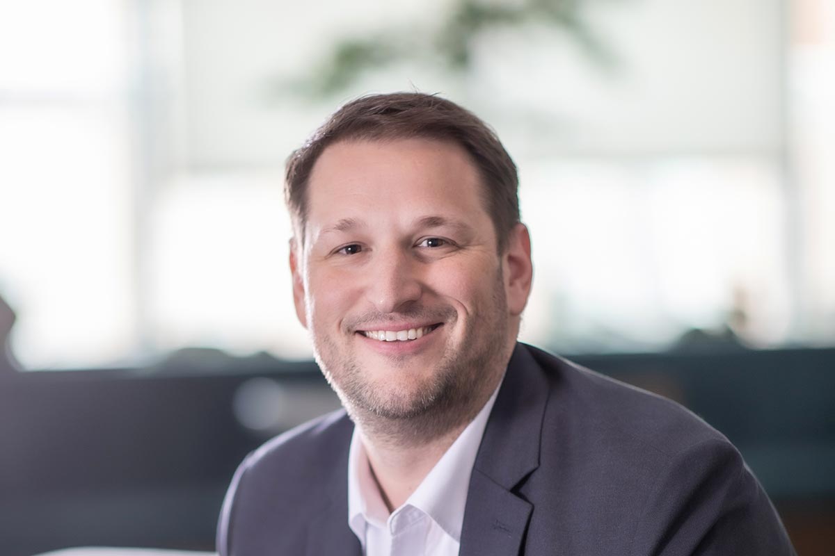 Jeremy Roehr, AIA, NCARB, Associate Principal and Studio Director of Education at GFF, close-up headshot in a blazer and white shirt with soft office background.