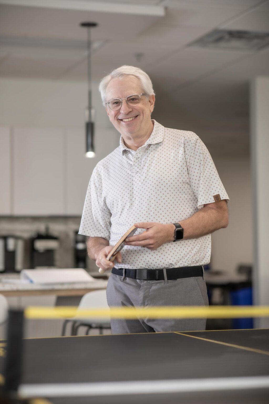 Lonnie Burns, Associate Principal and Studio Director at GFF, standing near a ping pong table in the Fort Worth office, smiling in patterned shirt.