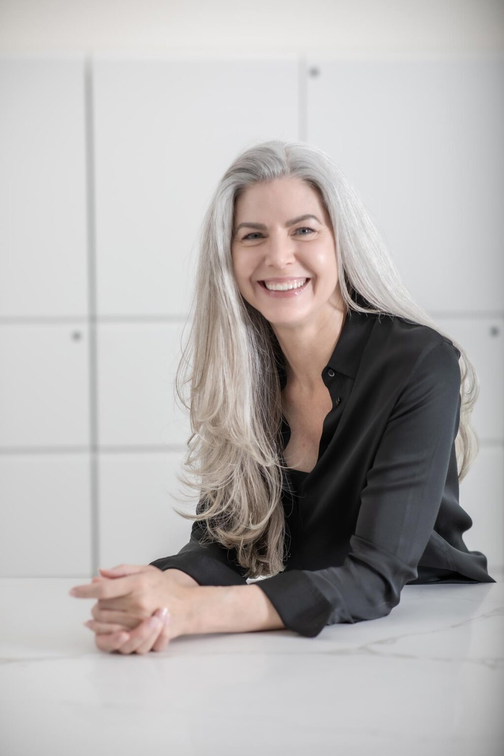 A portrait of Danielle Davis, Associate and Director of Accounting at GFF, leaning on a marble table and smiling in a modern white office interior.