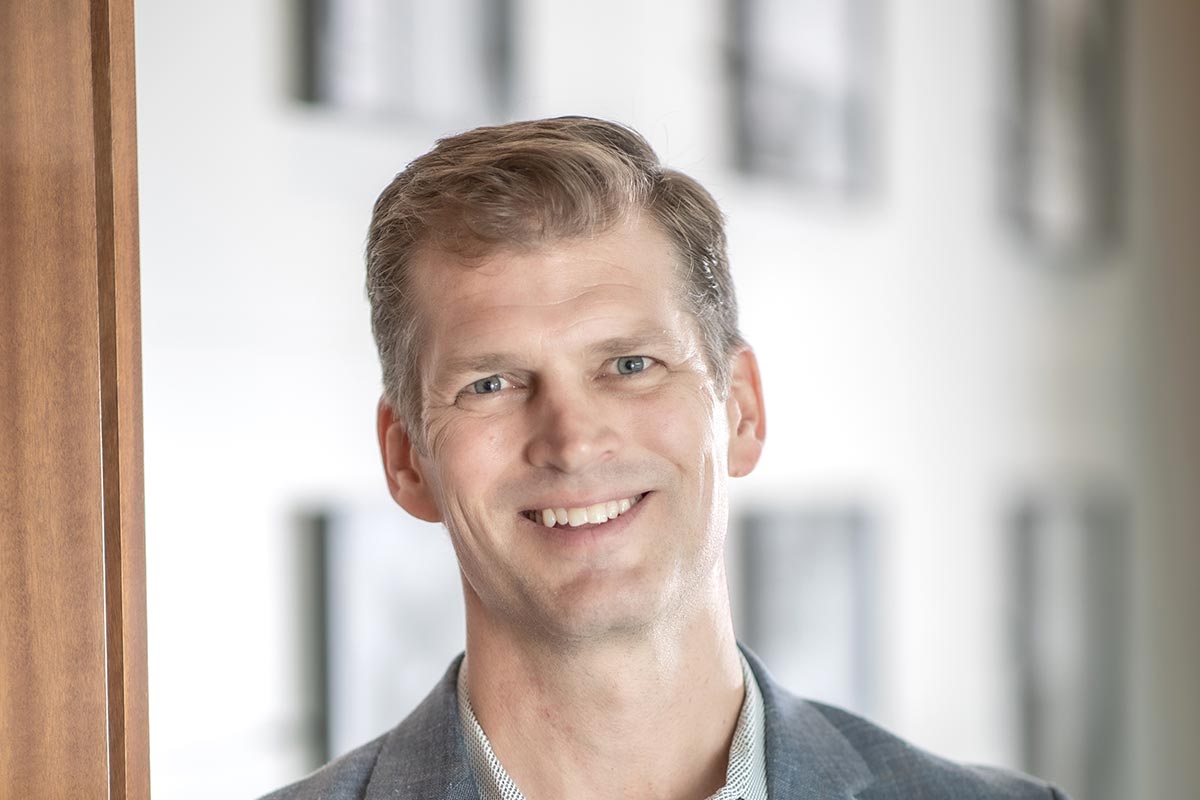 Grant Wickard, AIA, Associate Principal and Senior Project Leader at GFF, close-up portrait with blurred office background.