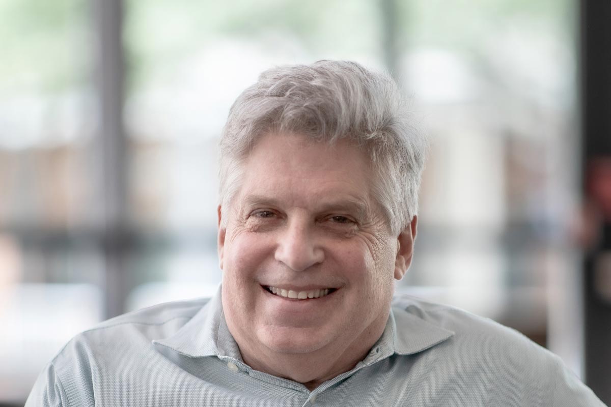 A cropped landscape portrait of Lance Braht, Associate Principal and Senior Design Leader at GFF, smiling in front of a softly lit modern office background.
