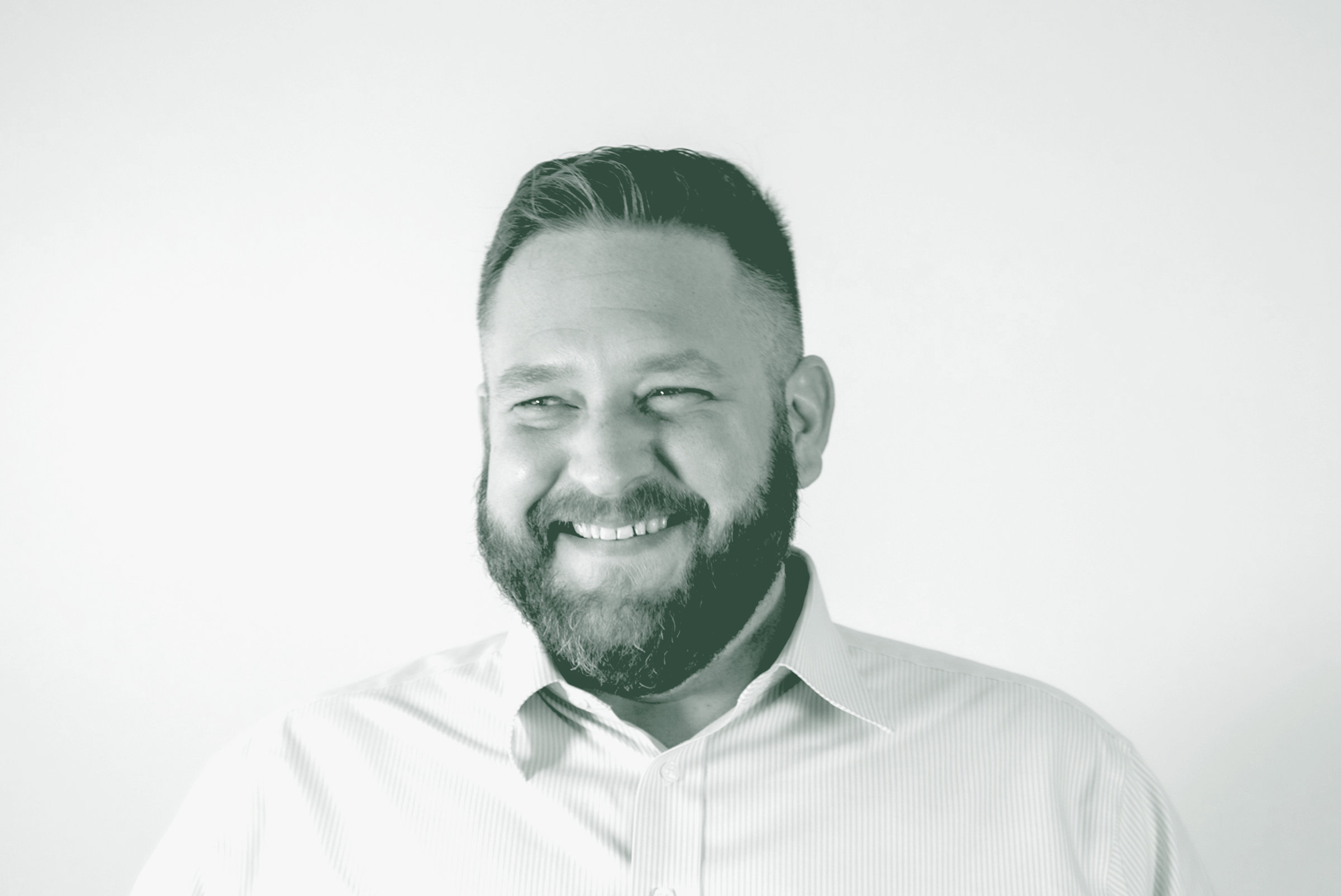 A black and white portrait of Scott Williams, a Senior Project Coordinator with GFF in the Faith & Community Studio, in front of a white background.