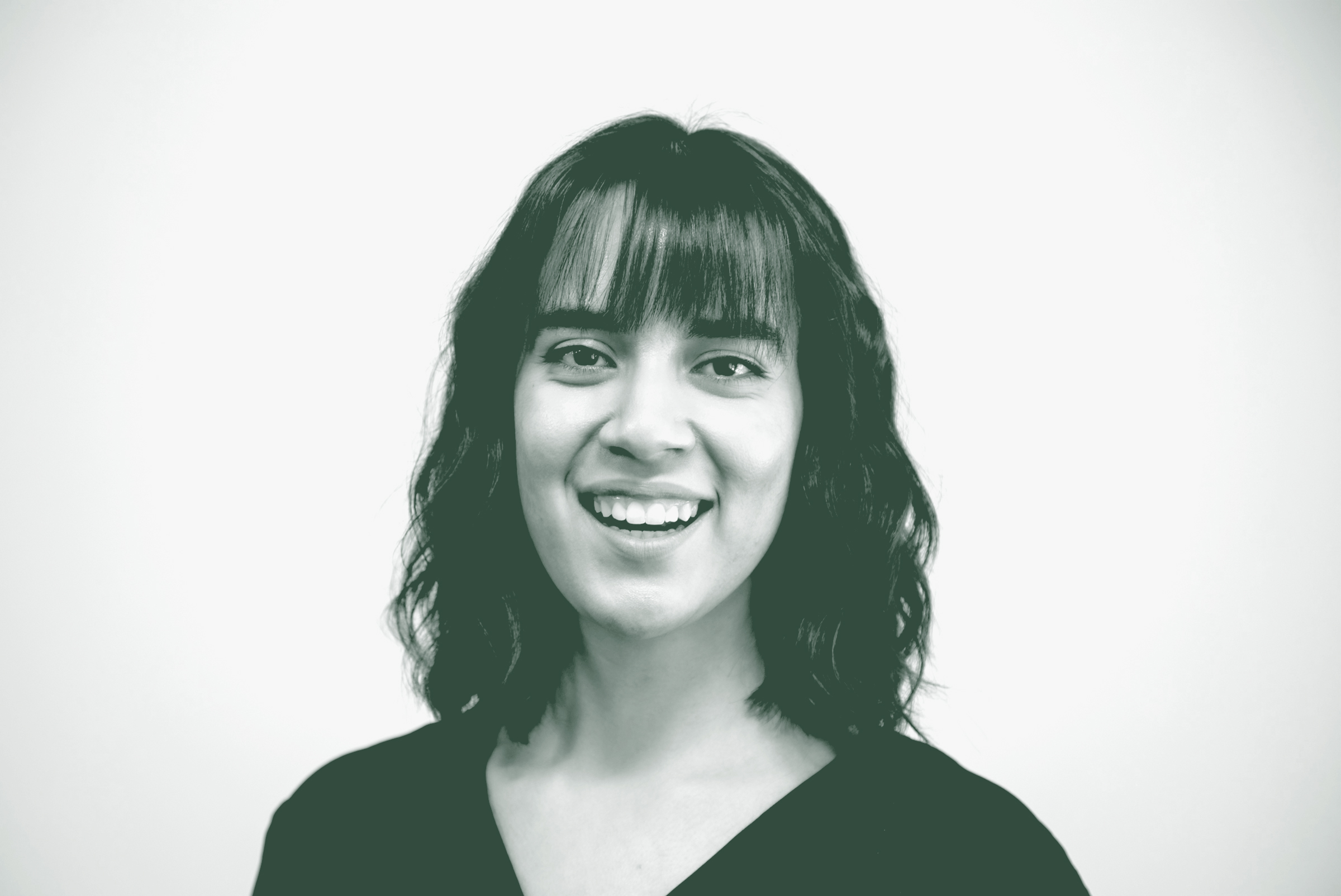 A black and white portrait of Syndey Galloso, a Project Coordinator with GFF in the Austin Studio, in front of a white background.