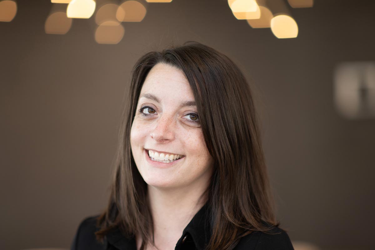 Beth Schmidt, RID, Associate and Senior Design Leader at GFF, close-up portrait with soft warm lights in the background.