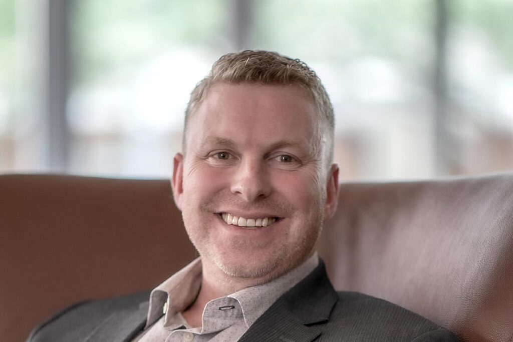 A cropped landscape portrait of Joshua Brown, Senior Project Coordinator at GFF, smiling in front of a softly lit modern office background.