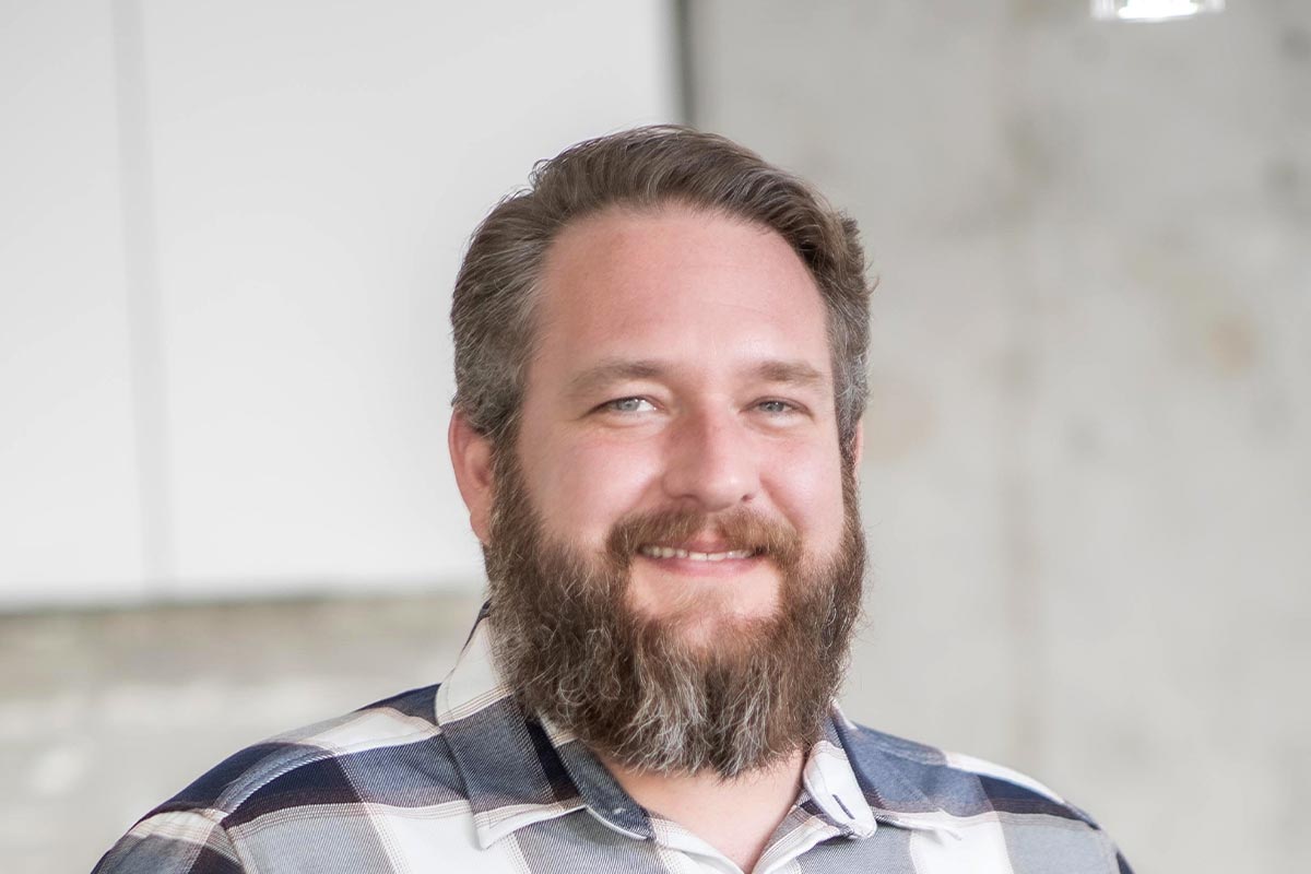 A cropped landscape portrait of Scott Williams, Senior Project Coordinator at GFF, smiling in front of a softly lit interior background.