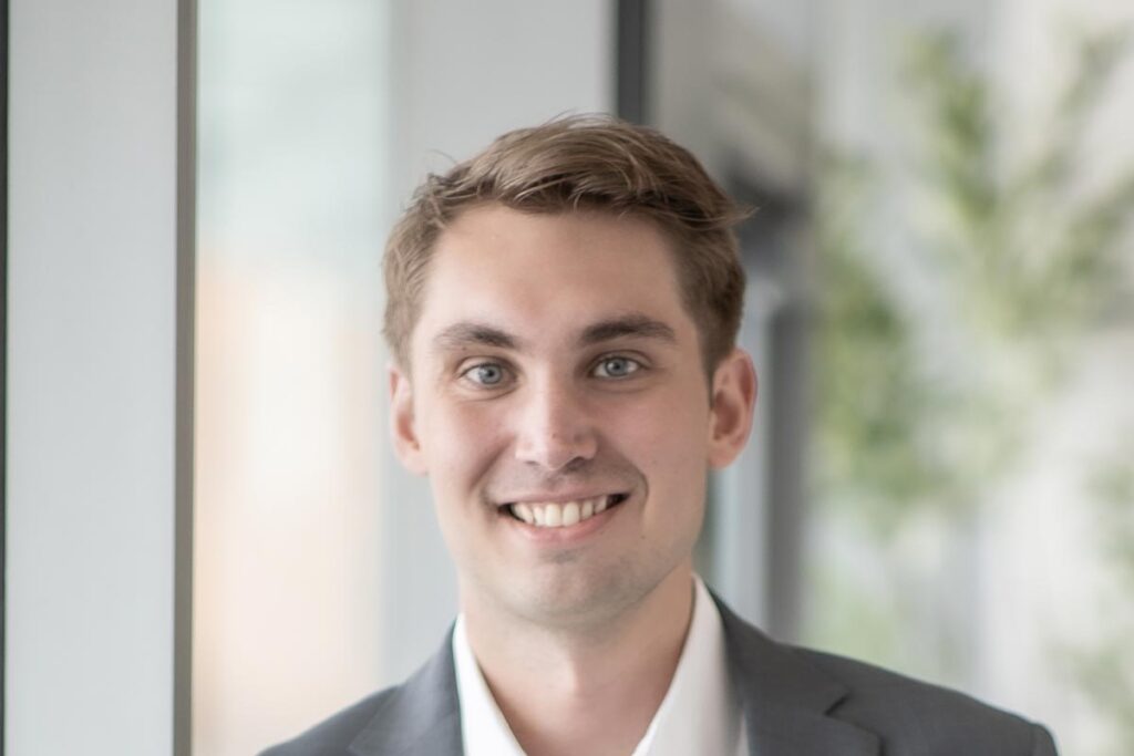 Carson Guy, Project Coordinator at GFF, close-up professional portrait with bright window light and soft background focus.