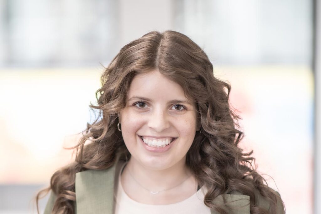 A cropped landscape portrait of Gabrielle Duran, Project Coordinator at GFF, smiling in front of a softly blurred background with warm window light.