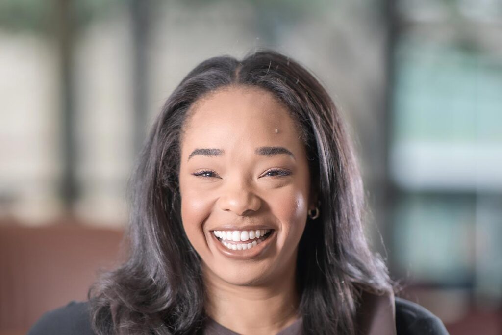 A cropped landscape portrait of Leah Coley, Architectural Professional at GFF, smiling in a softly lit interior setting.