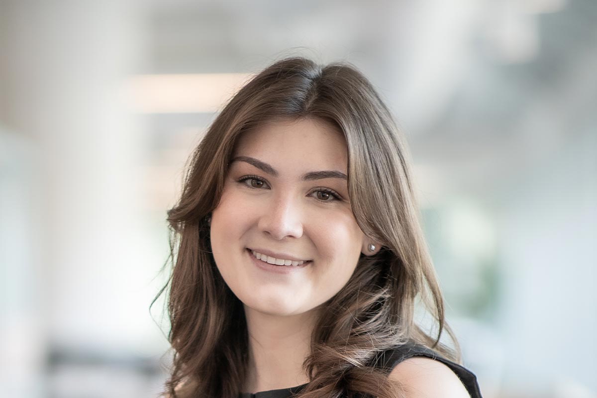A cropped landscape portrait of Natalie Hummell, Architectural Professional at GFF, smiling in a light-filled office interior.
