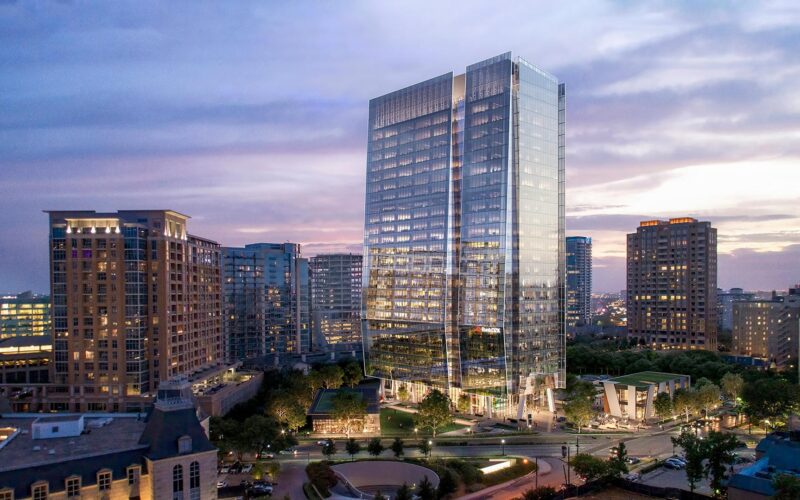 Skyline view of 23Springs in Uptown Dallas at dusk, showing the glass tower above its landscaped plaza and two street-facing restaurant buildings.