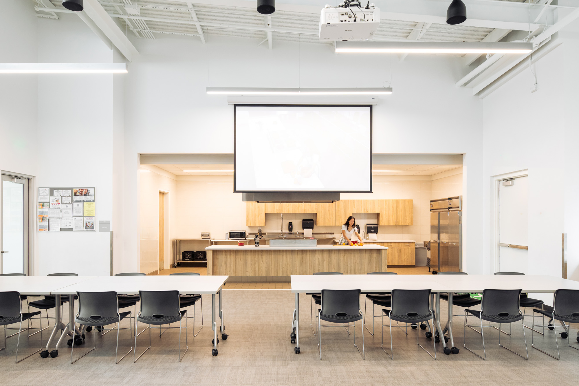 A bright, multi-functional community room with a demonstration kitchen and tables set up for group activities in the Diamond Hill Community Center.