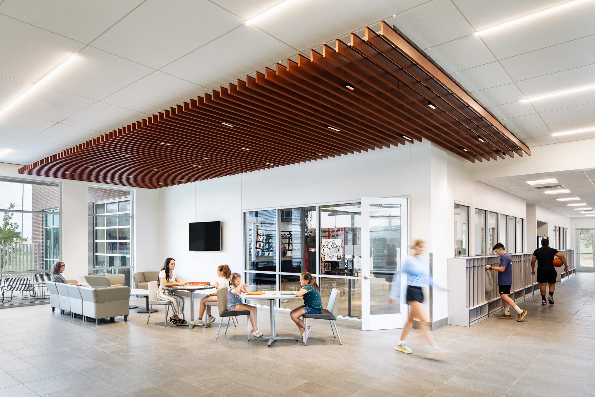 A lounge area in the Diamond Hill Community Center with families playing games and comfortable seating under a wooden slatted ceiling.