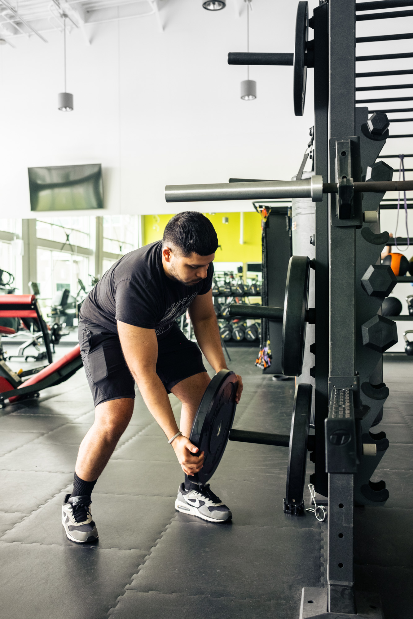 A man loading weights onto gym equipment in the fitness room at Diamond Hill Community Center.