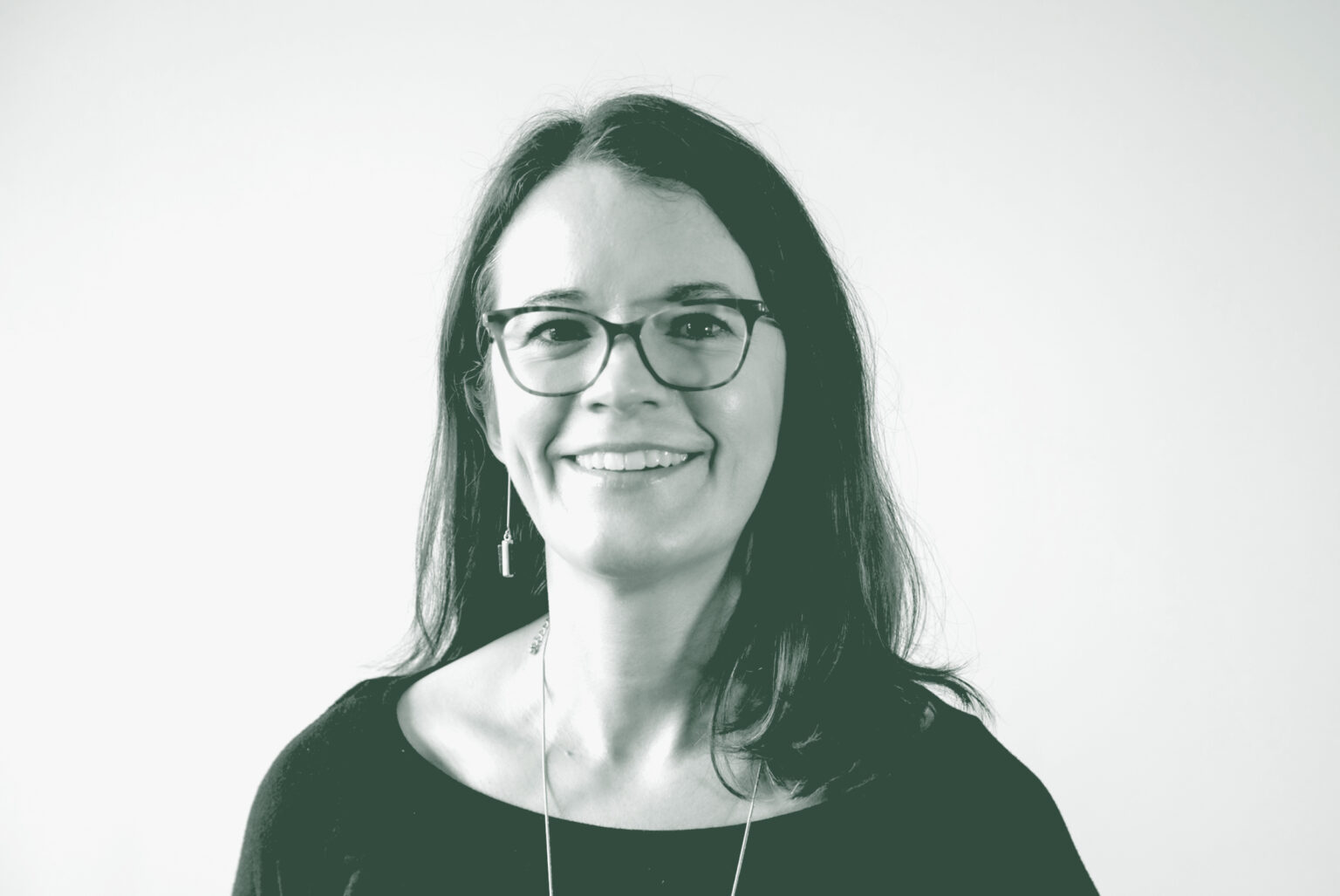 A black and white portrait of Jacquelyn Block, a Principal and the Director of Faith & Community Practice with GFF in the Faith & Community Studio, in front of a white background.