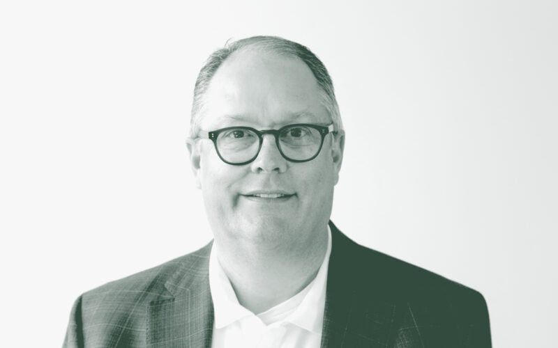 A black and white portrait of John Shiver, an Associate Principal and the Director of Education Practice with GFF in the K-12 & Higher Ed Studio, in front of a white background.
