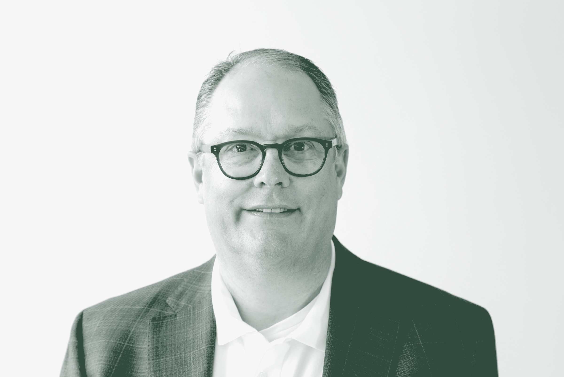 A black and white portrait of John Shiver, an Associate Principal and the Director of Education Practice with GFF in the K-12 & Higher Ed Studio, in front of a white background.