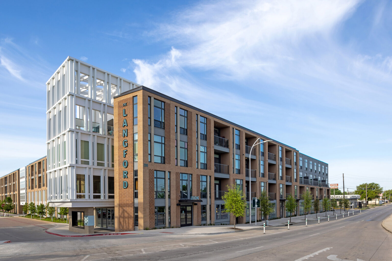 Street view of The Langford's modern four-story residential building with brick detailing, large windows, and balconies.