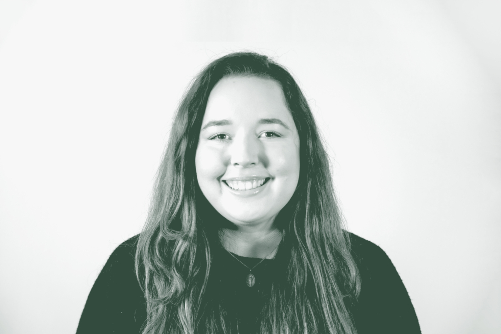 A black and white portrait of Camille Vigil, a Project Coordinator with GFF in the Faith & Community Studio, in front of a white background.