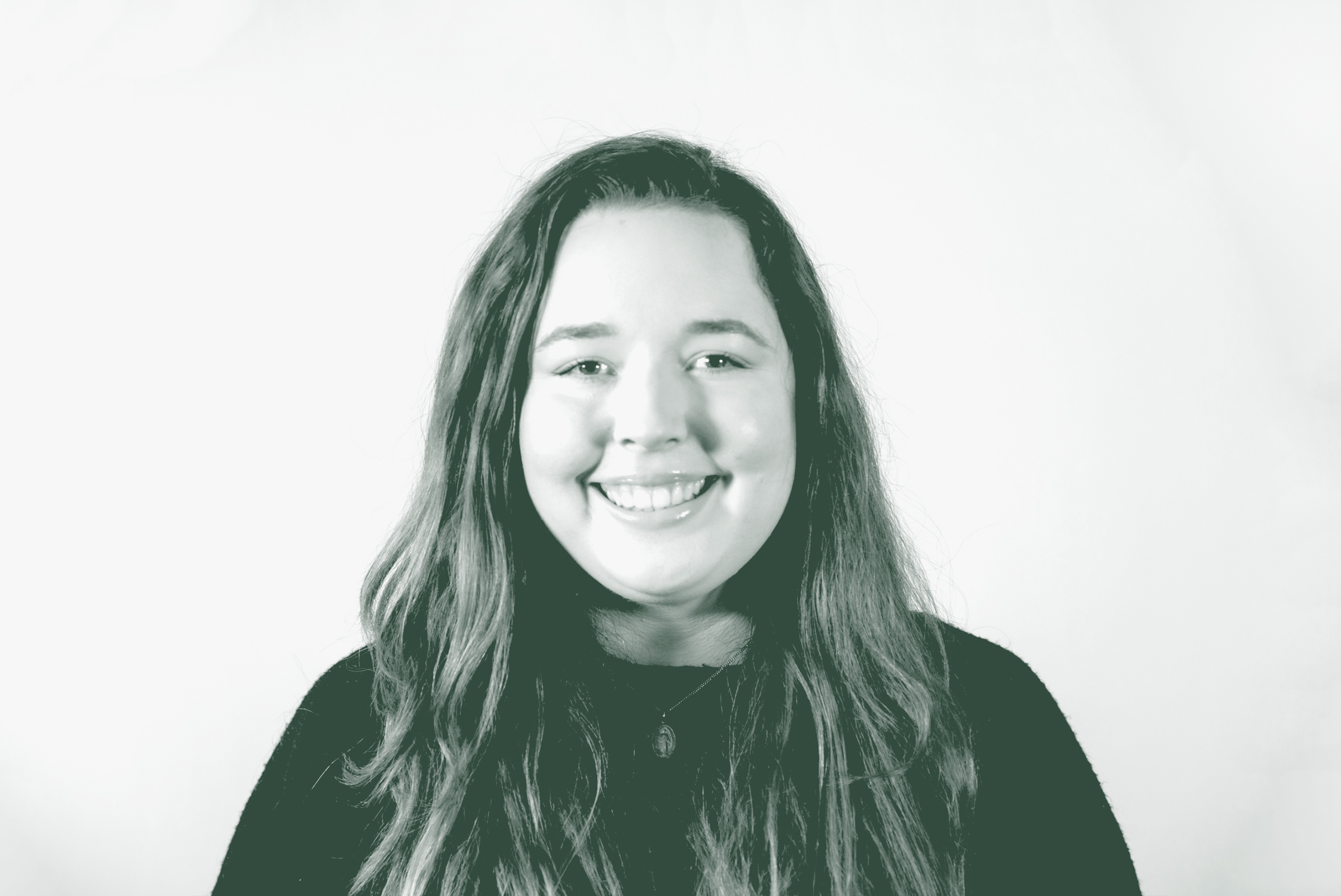 A black and white portrait of Camille Vigil, a Project Coordinator with GFF in the Faith & Community Studio, in front of a white background.