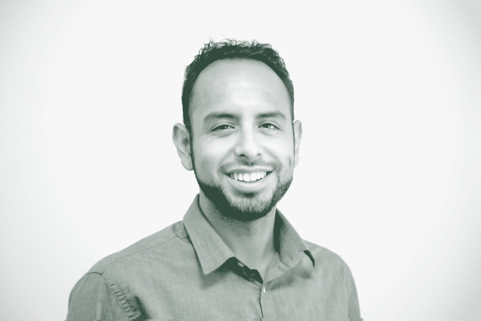 A black and white portrait of Jake Chavez, a Senior Project Coordinator with GFF in the Austin Studio, in front of a white background.