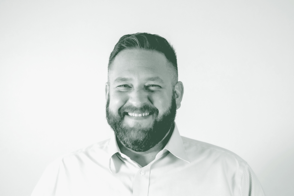 A black and white portrait of Scott Williams, a Senior Project Coordinator with GFF in the Faith & Community Studio, in front of a white background.