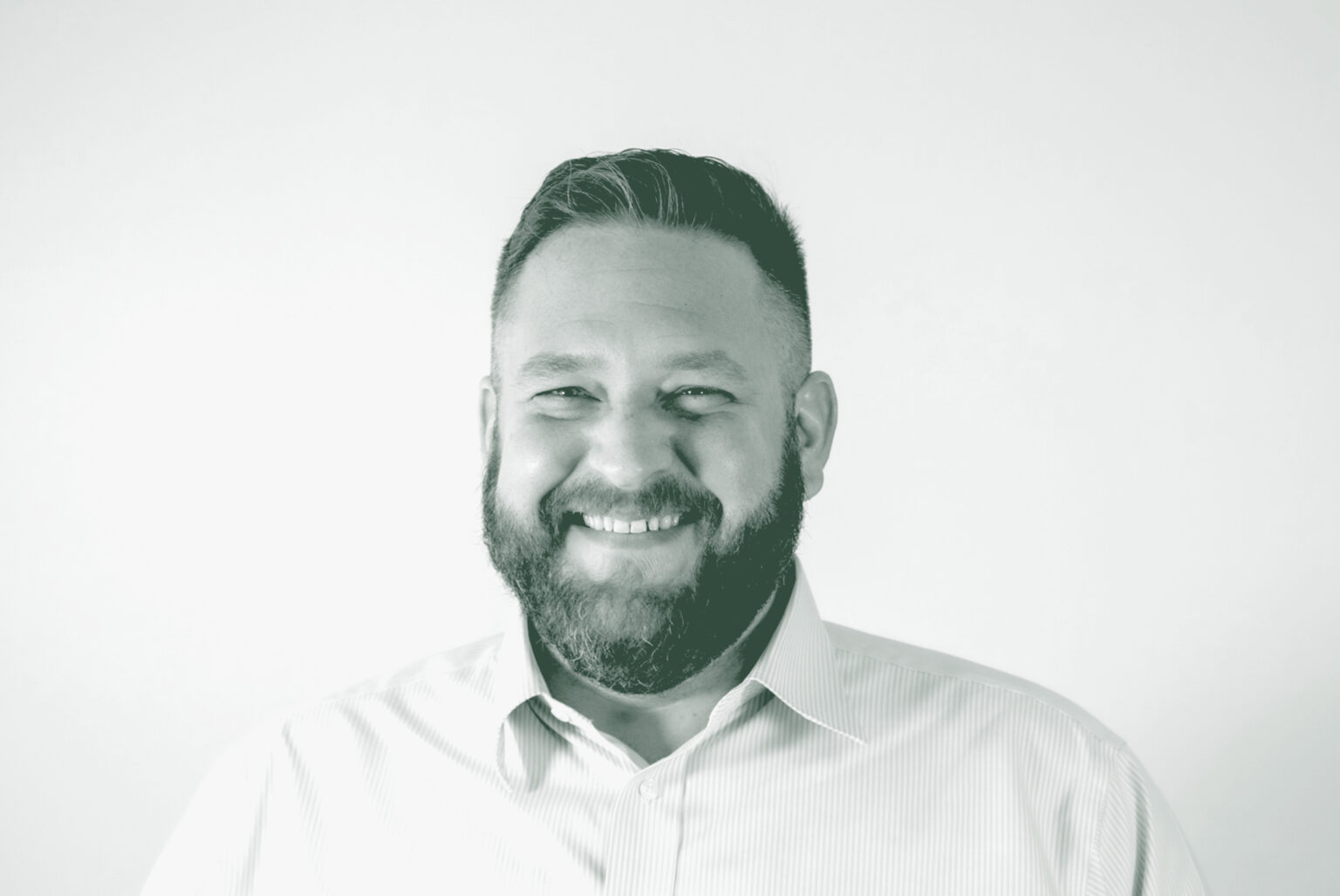 A black and white portrait of Scott Williams, a Senior Project Coordinator with GFF in the Faith & Community Studio, in front of a white background.