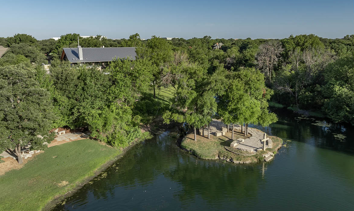 Aerial view of St. Andrew UMC - Hasley Chapel overlooking a tranquil creek and pond surrounded by lush greenery in Plano, Texas