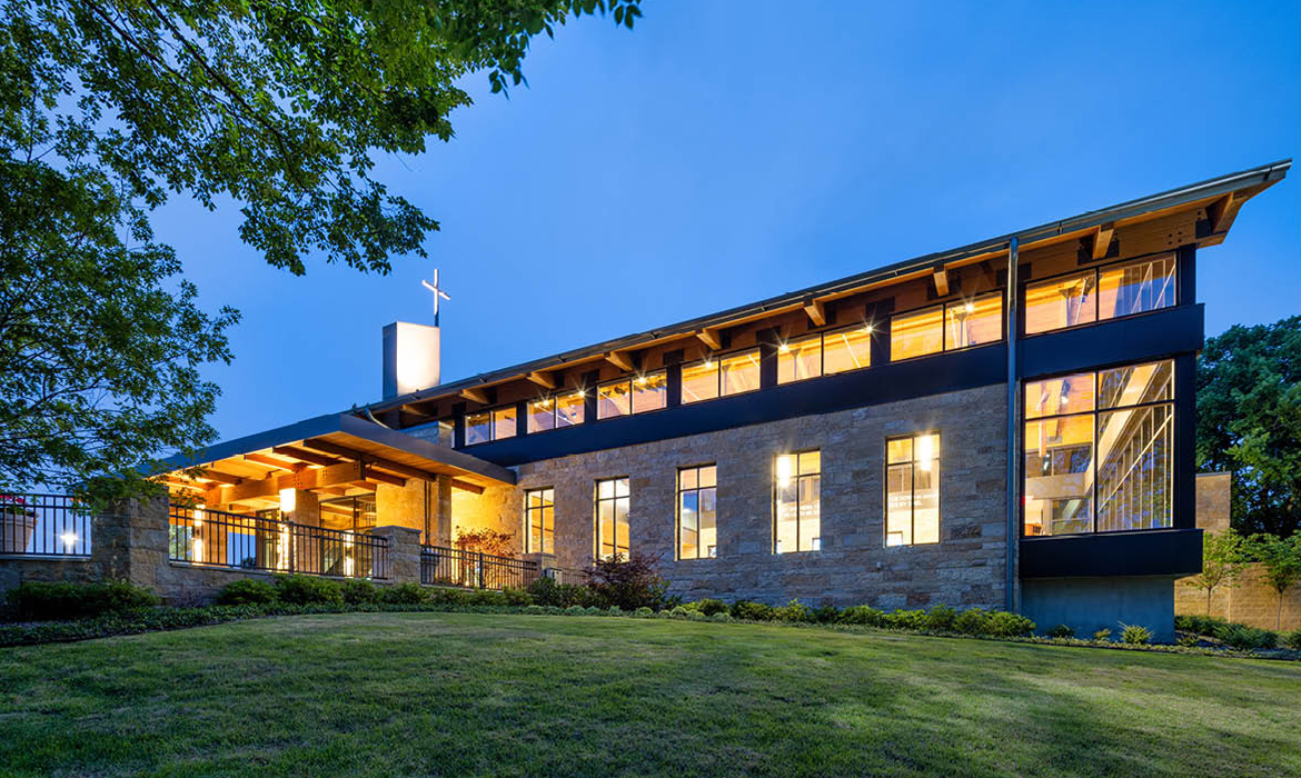 Side view of Hasley Chapel at night, showcasing its modern facade with stone and glass elements.