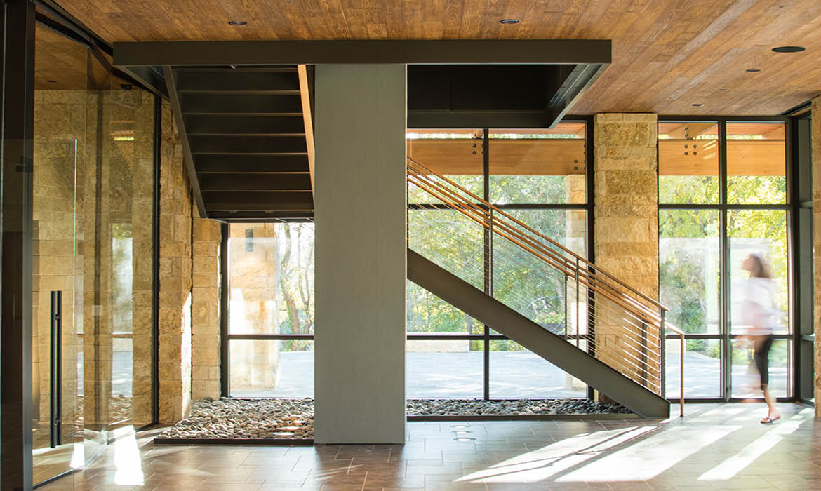 Interior staircase of Hasley Chapel with natural wood finishes, stone walls, and floor-to-ceiling windows.