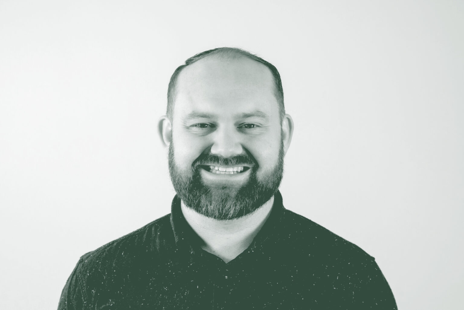 A black and white portrait of Tyler Porter, a Senior Project Coordinator with GFF in the Fort Worth Studio, in front of a white background.