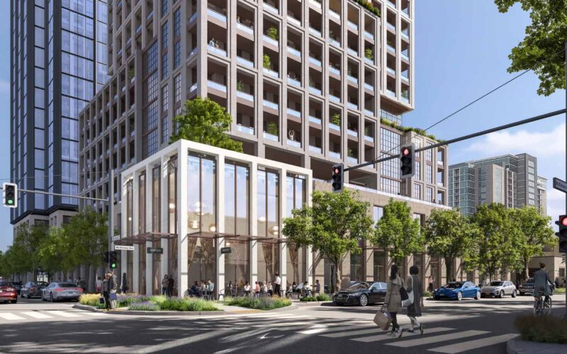 Street-level view of the intersection of McKinney and Armstrong with a modern glass structure and pedestrian activity.