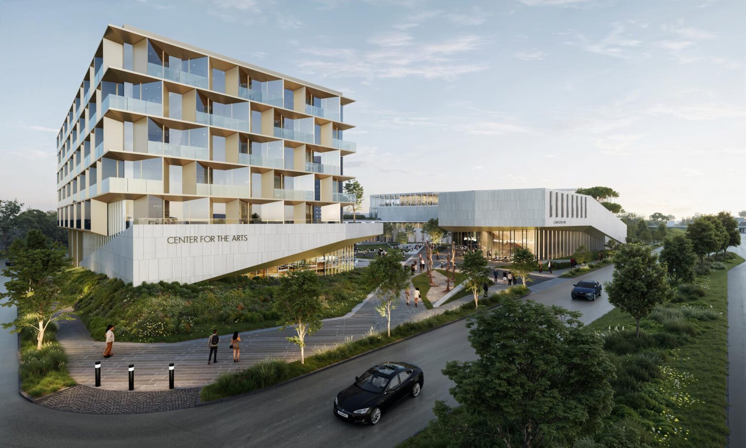 View of the Center for the Arts campus highlighting the live-work housing block and main building connected by a landscaped pedestrian walkway above a green slope.