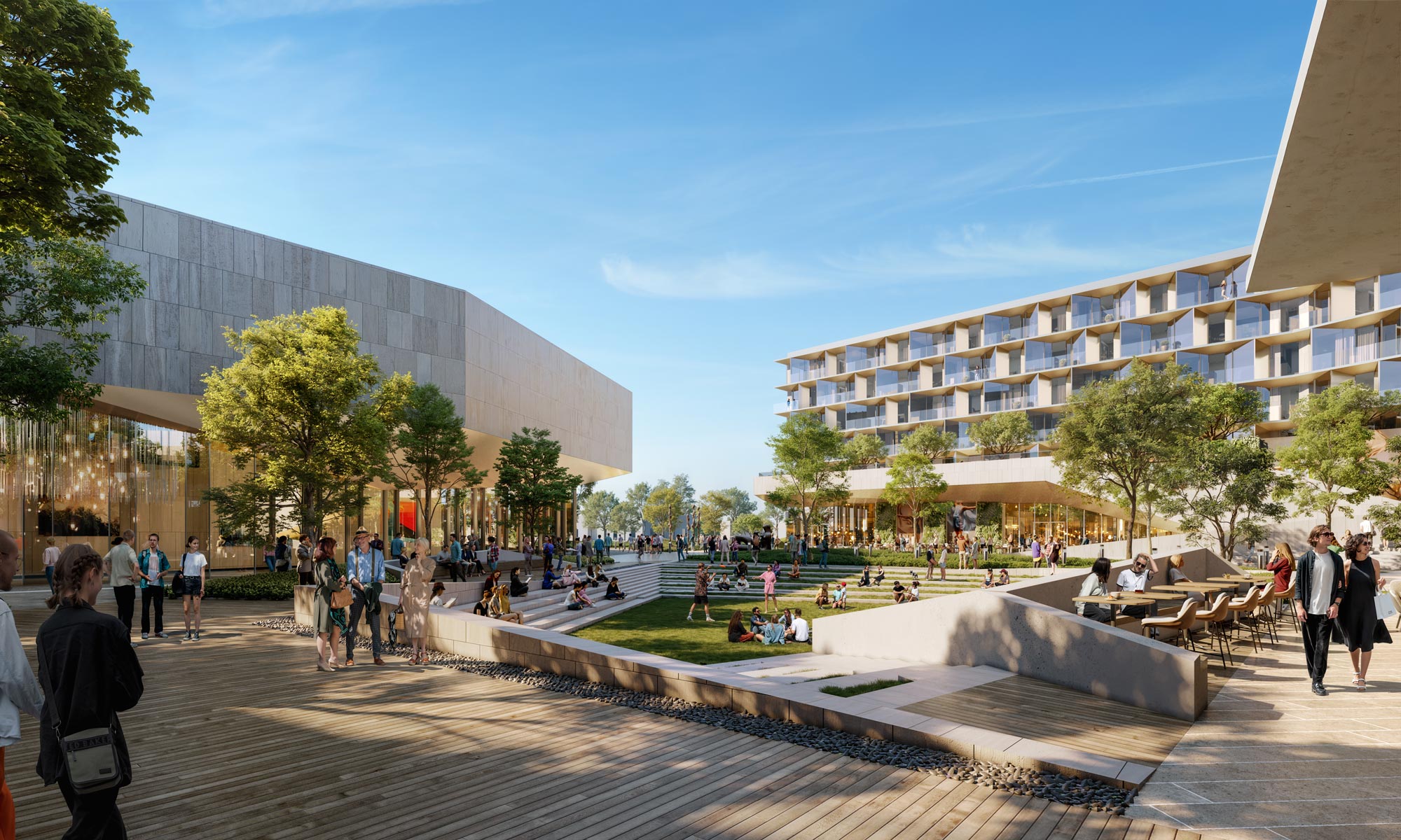 Daytime view of the central courtyard at the Center for the Arts, featuring stepped lawn seating, shaded trees, and transparent ground-floor façades that connect interior studios to outdoor gathering spaces.