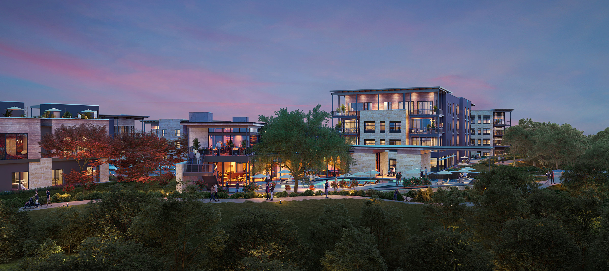 Amenity area at dusk with views of modern multifamily buildings at Pearl Bee Cave, TX, featuring warm exterior lighting, lush trees, and landscaped walkways.