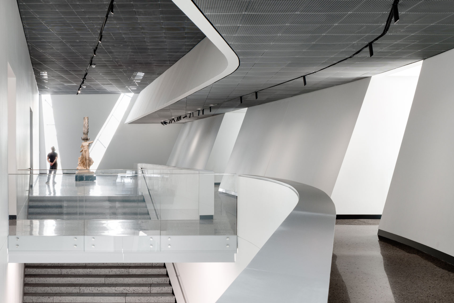 Interior circulation space in UT Dallas Athenaeum, featuring a sculpture and skylit architecture.