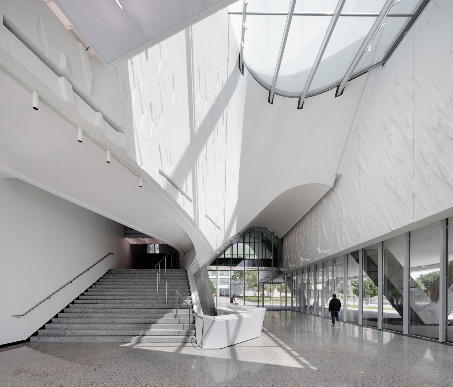 Skylit circulation space in UT Dallas Athenaeum, featuring a sculptural stairway.