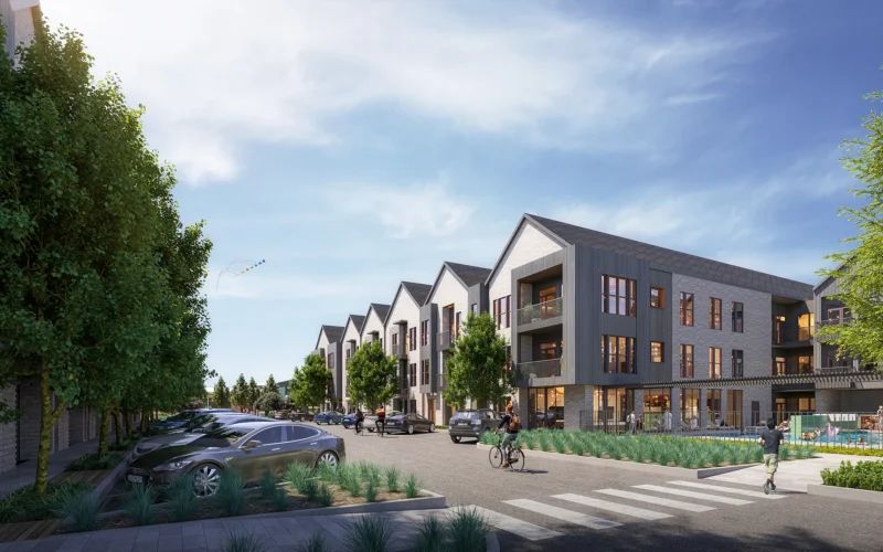Street-level rendering of contemporary multifamily residences at Assembly Park, featuring a row of gabled buildings clad in a mix of stone, metal panels, and large windows. A landscaped streetscape with parked cars, bikers, and pedestrians enhances the walkability of the area. In the foreground, a pool and lounge space are enclosed by a low fence.